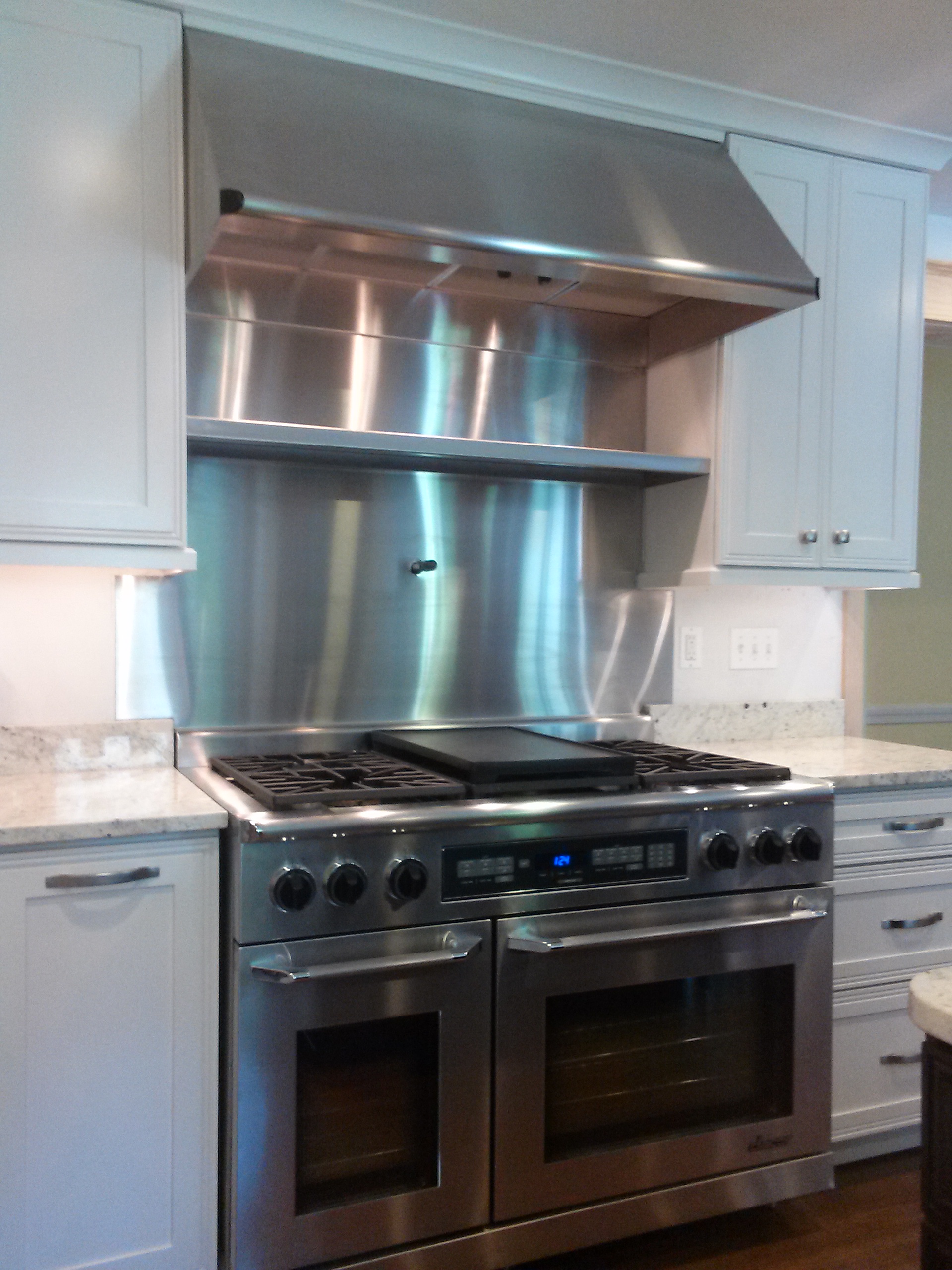 ANBIZA stainless steel backsplash behind a professional range in a residential kitchen