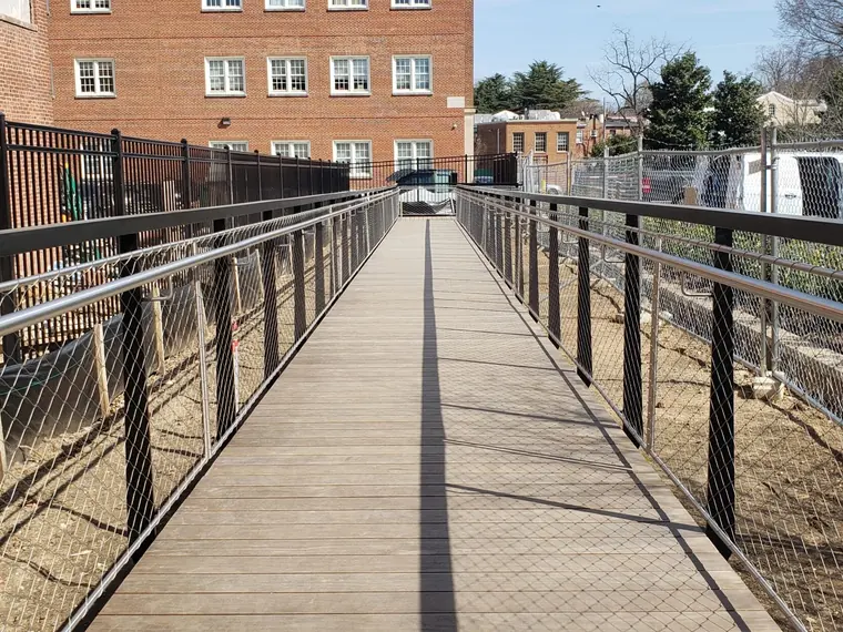 Commercial accessibility ramp with stainless steel mesh railings, built by Anchor Business Agency